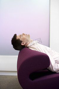 一位男性高管睡在办公室现代沙发上的侧视图