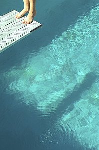 游泳池上方跳板末端向后站立的女潜水员的特写低部