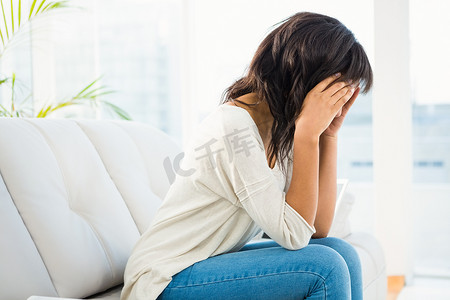 悲观情绪摄影照片_女人坐在沙发上抱着头
