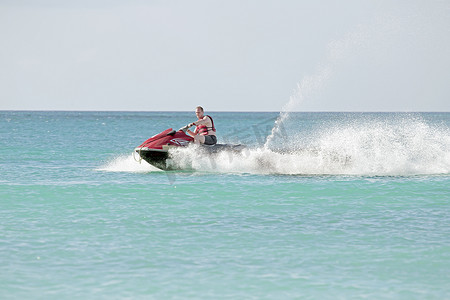 海边船摄影照片_乘坐摩托艇在加勒比海巡航的年轻人