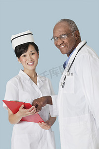 医疗帽子摄影照片_浅蓝色背景下快乐医疗专业人员讨论医疗报告的肖像
