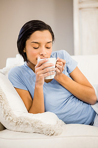 平静的黑发女人用白杯喝酒