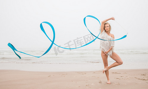 跳舞丝带摄影照片_体操女子在海滩上用丝带跳舞