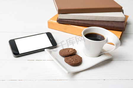 带饼干、电话和一摞书的咖啡杯