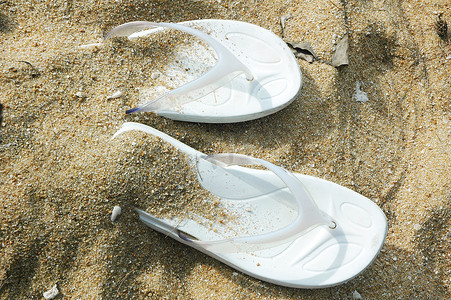 字金色沙子摄影照片_沙滩上的凉鞋