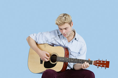 蓝色背景下弹吉他的年轻人