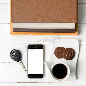 带饼干、电话、车钥匙和一摞书的咖啡杯