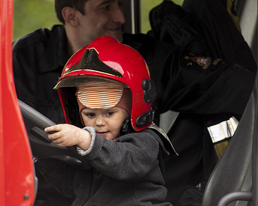 消防车里戴着消防员头盔的孩子