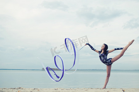 跳舞丝带摄影照片_年轻的体操运动员女孩用丝带跳舞