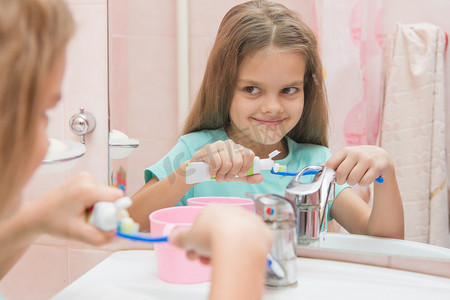 挤牛奶摄影照片_快乐的小女孩从牙刷管里挤牙膏