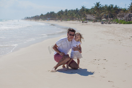 快乐的父亲带着可爱的女儿在热带海滩度假