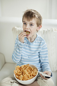 男孩边看电视边吃轮状零食颗粒