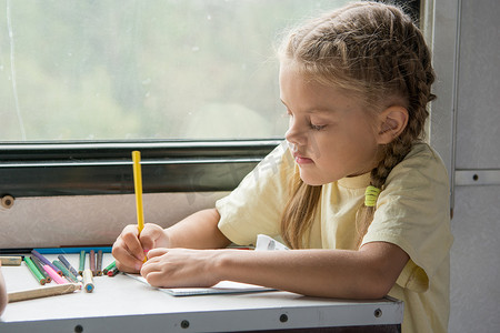 六岁女孩在二等车厢里用铅笔画画