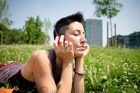室外音乐摄影照片_美丽的时髦短发女人在公园里听音乐