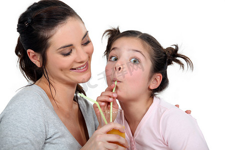 喝饮料的女孩摄影照片_母亲和女儿用吸管喝酒