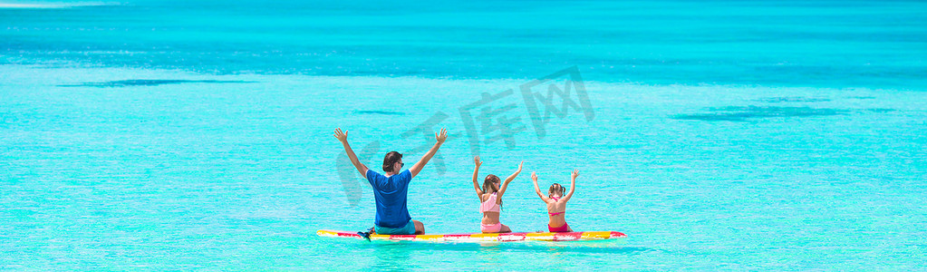 暑假期间冲浪板上的小女孩和年轻爸爸
