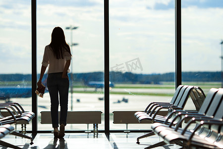 机场休息室窗边等待飞机的年轻女子