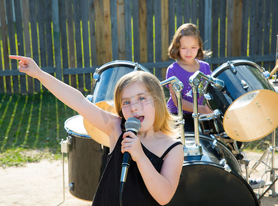 儿童乐队摄影照片_儿童歌手女孩在后院演奏现场乐队唱歌