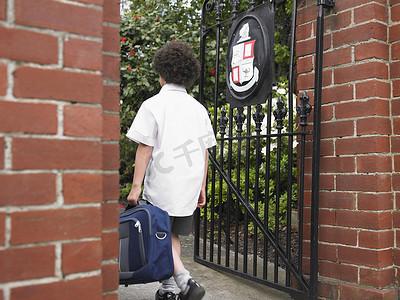 背着背包的小男孩进入校门的后视图