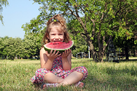 吃女孩西瓜摄影照片_小女孩坐在草地上吃西瓜