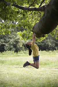 挂在树枝上的女孩的全长侧视图