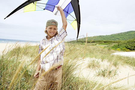 海滩上举起双臂、头顶放风筝的快乐小男孩的肖像