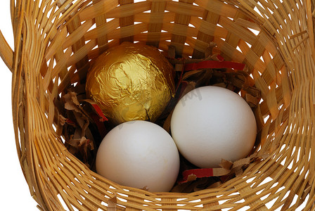 金丹和鸡蛋摄影照片_篮子里有一个金鸡蛋和两个白鸡蛋