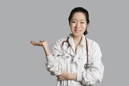 一位亚洲女医生在灰色背景下展示隐形产品的肖像