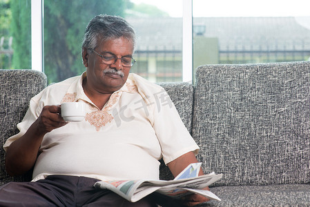 印度老年人一边看报纸一边喝咖啡