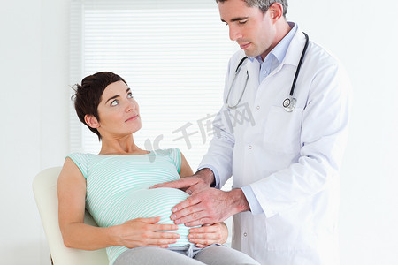 腹诊摄影照片_医生听诊孕妇的腹部