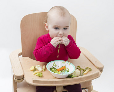 年幼的孩子在高脚椅上吃饭