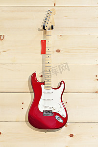 木纹墙上的 Fender Stratocaster 红色和白色吉他