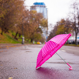 海滨城市图片摄影照片_户外湿沥青上的粉色儿童伞