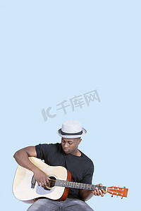 浅蓝色背景中弹吉他的年轻非洲裔美国人