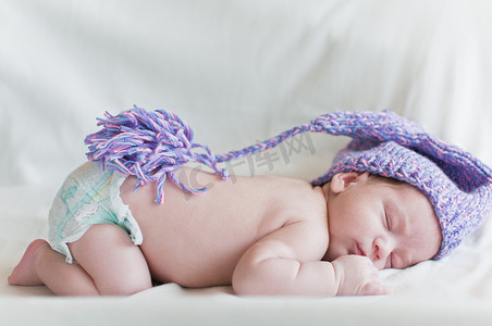 戴着紫色帽子睡觉的婴儿