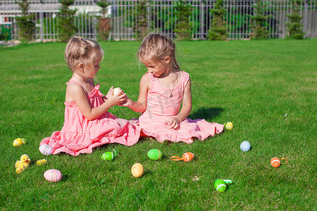 两个可爱的小女孩在绿草上玩复活节彩蛋
