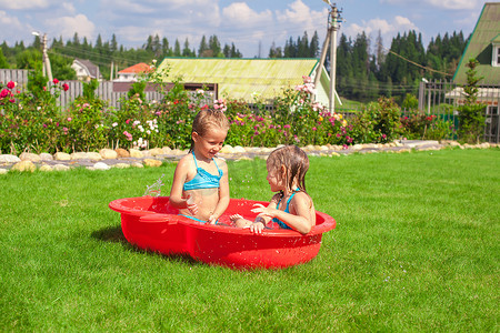 阳光明媚的炎热日子里，两个小姐妹在泳池里玩耍、戏水