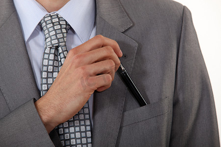 一名男子将钢笔放入口袋的裁剪照片。