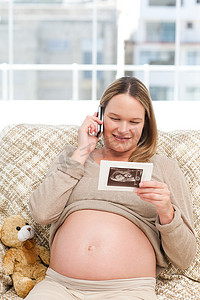 快乐的孕妇一边打电话一边看回波描记术