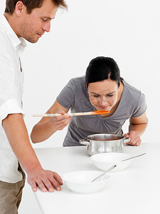 可爱的女人和丈夫在厨房里品尝汤