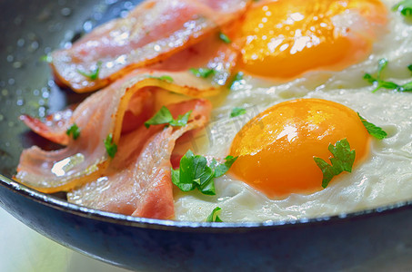 煮熟的鸡蛋摄影照片_在煎锅中煎鸡蛋和培根