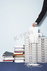 空间撕碎摄影照片_裁剪后的商人在办公室的一堆文件夹旁边撕碎文件