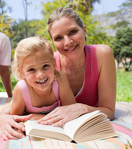 快乐的母亲和她的女儿在公园读书