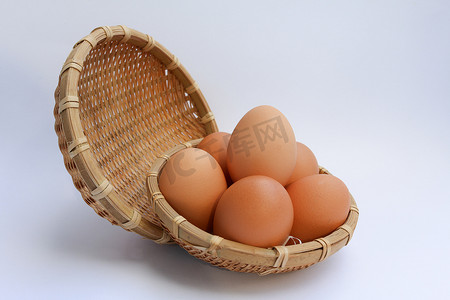 蛋黄摄影照片_白色背景上篮子柳条中的鸡蛋