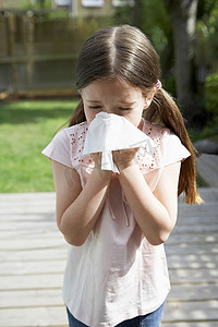 小女孩在后院用纸巾擤鼻涕