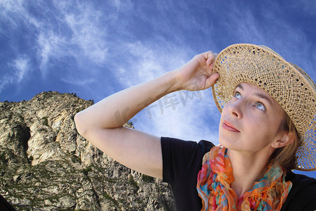一个戴着帽子的女人饶有兴趣地抬头看着蓝天