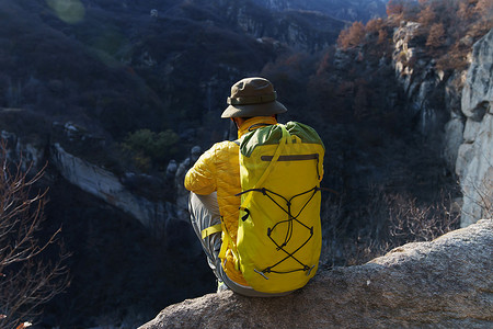 青年登山者坐在山顶俯瞰