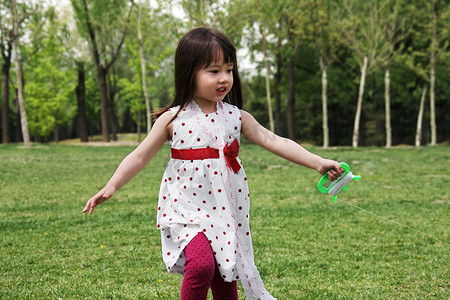 风筝玩具摄影照片_一个小女孩在户外玩耍