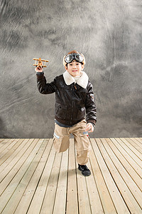 木质飞机模型摄影照片_拿着飞机模型奔跑的快乐男孩