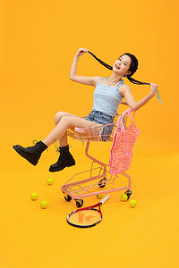 网球少女摄影照片_充满活力的年轻女孩坐在购物车上